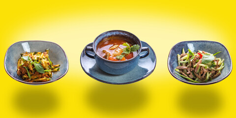 Three dishes: two types of salad and borscht on a yellow isolated background. The concept of restaurant service. Business lunch.