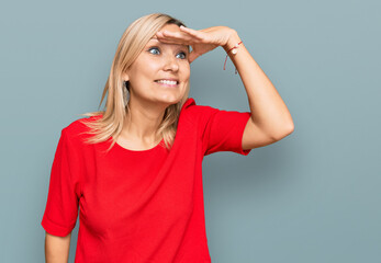 Fototapeta premium Middle age caucasian woman wearing casual clothes very happy and smiling looking far away with hand over head. searching concept.