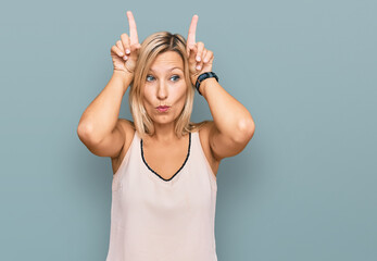 Middle age caucasian woman wearing casual clothes doing funny gesture with finger over head as bull horns