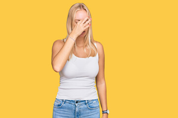 Young blonde girl wearing casual style with sleeveless shirt tired rubbing nose and eyes feeling fatigue and headache. stress and frustration concept.