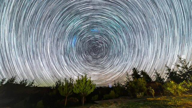 The stars moving around the night sky keeping it trails as it turn around the celestial equator. An amazing starry night view to see the Earth rotation movement in the sky at an idyllic landscape