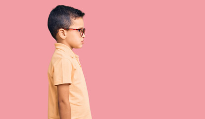 Little cute boy kid wearing casual clothes and glasses looking to side, relax profile pose with...