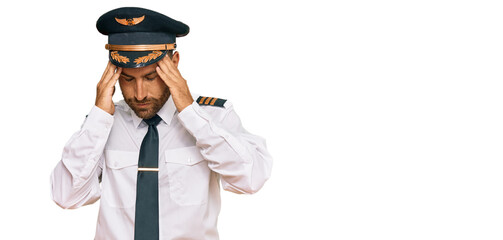 Handsome man with beard wearing airplane pilot uniform with hand on head for pain in head because stress. suffering migraine. © Krakenimages.com