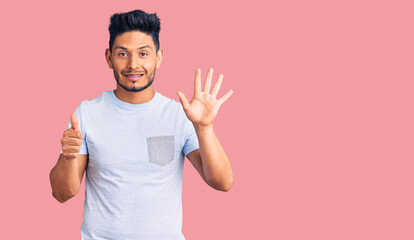 Handsome latin american young man wearing casual clothes showing and pointing up with fingers number six while smiling confident and happy.