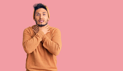 Fototapeta premium Handsome latin american young man wearing winter sweater and wool hat shouting and suffocate because painful strangle. health problem. asphyxiate and suicide concept.