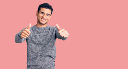 Hispanic handsome young man wearing casual sweater approving doing positive gesture with hand,...