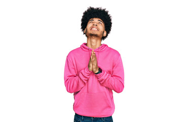 Young african american man with afro hair wearing casual pink sweatshirt begging and praying with...