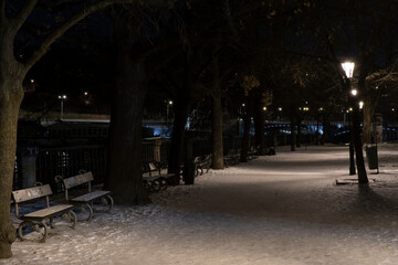 .light from street lights and a walkway sunken with snow in the center of Prague in the park at night