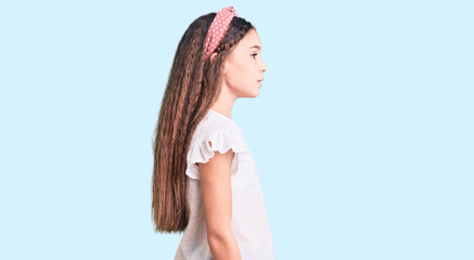 Fototapeta premium Cute hispanic child girl wearing casual white tshirt looking to side, relax profile pose with natural face and confident smile.