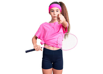 Cute hispanic child girl holding badminton racket pointing with finger to the camera and to you, confident gesture looking serious