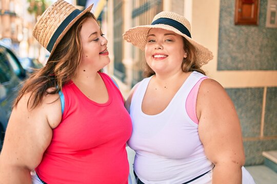 Two plus size overweight sisters twins women hugging together outdoors