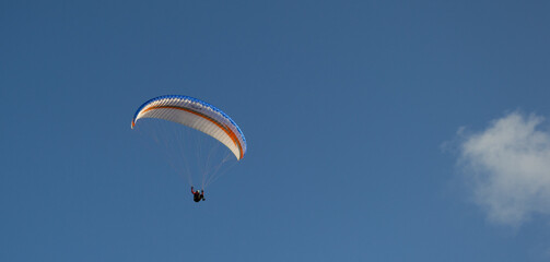 A beautiful view of a paraglide flying gliding on a clear blue sky at the golden hour with a nice wind windy breeze on a sunny day 