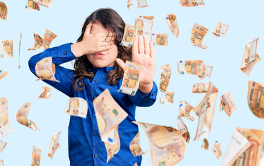 Cute child with long hair wearing casual clothes covering eyes with hands and doing stop gesture with sad and fear expression. embarrassed and negative concept.