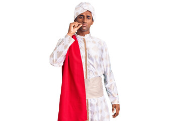 African handsome man wearing tradition sherwani saree clothes mouth and lips shut as zip with fingers. secret and silent, taboo talking