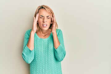 Beautiful blonde woman wearing casual winter sweater with hand on head for pain in head because stress. suffering migraine.