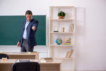 Young male teacher in front of green board