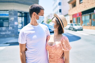 Beautiful couple wearing medical mask walking at street of city