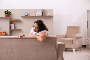 Young lazy man in oversleeping concept at home