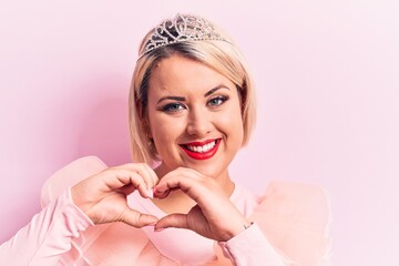 Beautiful blonde plus size woman wearing pincess tiara with diamonds over pink background smiling...