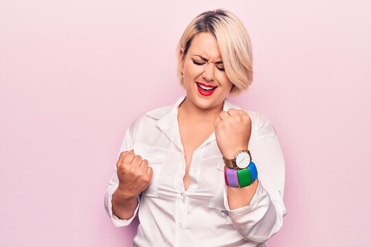 Young beautiful blonde plus size woman wearing elegant shirt over isolated pink background celebrating surprised and amazed for success with arms raised and eyes closed