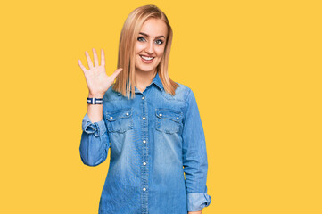 Beautiful caucasian woman wearing casual denim jacket showing and pointing up with fingers number five while smiling confident and happy.