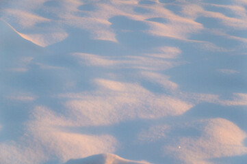 winter background: snowy field, lit by the setting sun, late evening