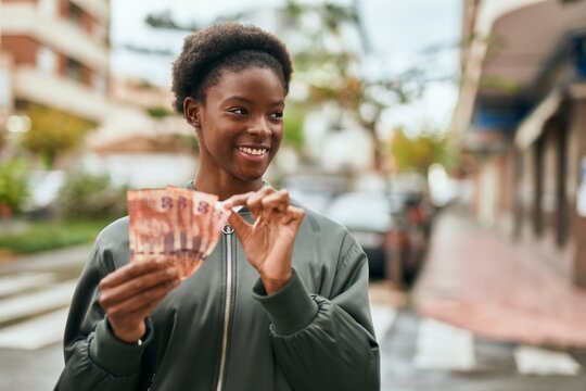 Young african american girl smiling happy counting south africa rands at the city.