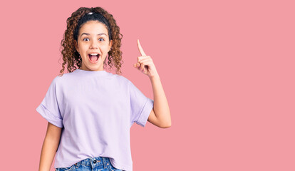 Beautiful kid girl with curly hair wearing casual clothes pointing finger up with successful idea....