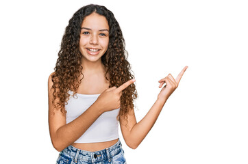 Teenager hispanic girl wearing casual clothes smiling and looking at the camera pointing with two hands and fingers to the side.