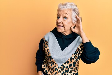 Senior grey-haired woman wearing sportswear smiling with hand over ear listening and hearing to...
