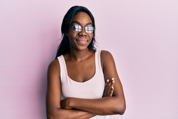 Young african american woman wearing casual clothes and glasses happy face smiling with crossed arms looking at the camera. positive person.