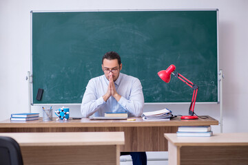Young male teacher in front of green board