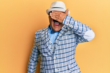 Mature middle east man with mustache wearing vintage and elegant fashion style smiling and laughing with hand on face covering eyes for surprise. blind concept.