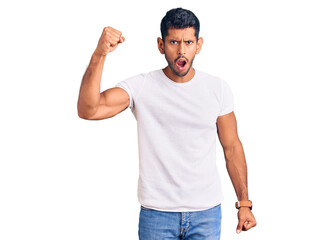 Fototapeta premium Young latin man wearing casual clothes angry and mad raising fist frustrated and furious while shouting with anger. rage and aggressive concept.