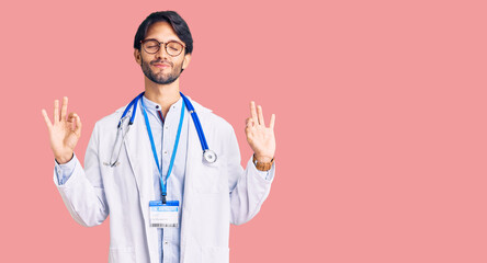 Handsome hispanic man wearing doctor uniform and stethoscope relax and smiling with eyes closed doing meditation gesture with fingers. yoga concept.
