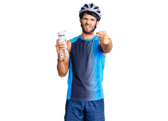 Handsome hispanic man wearing bike helmet and holding water bottle annoyed and frustrated shouting with anger, yelling crazy with anger and hand raised