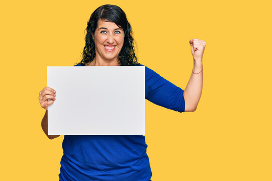 Plus size brunette woman holding blank empty banner pointing finger to one self smiling happy and proud