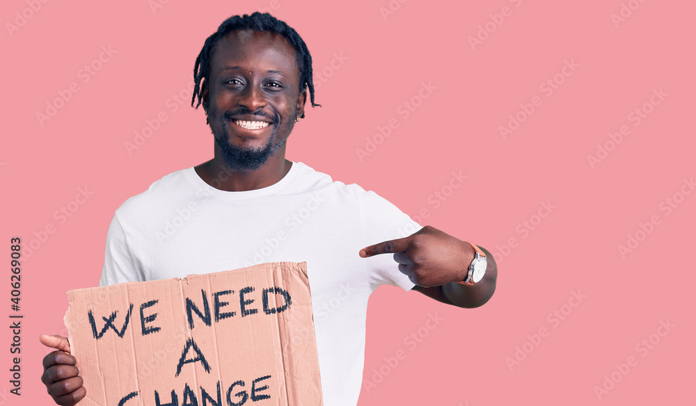 Sticker young african american man with braids holding we need a change banner pointing finger to one self s