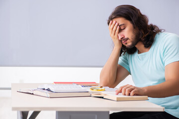 Young male student preparing for exams in the classroom