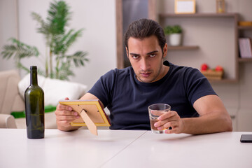 Young male alcoholic suffering from unhappy love at home