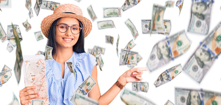 Young beautiful latin girl wearing summer hat holding map smiling happy pointing with hand and finger to the side
