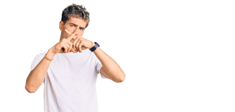 Young handsome man wearing casual white tshirt rejection expression crossing fingers doing negative sign