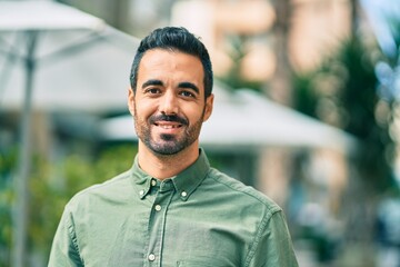 Young hispanic man smiling happy standing at the city.
