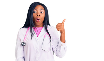 Young african american woman wearing doctor stethoscope surprised pointing with hand finger to the side, open mouth amazed expression.