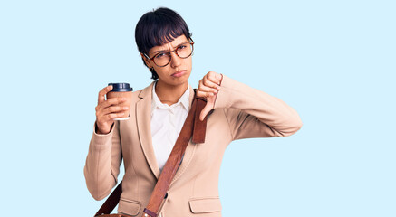 Young brunette woman with short hair wearing business bag and drinking coffee with angry face,...