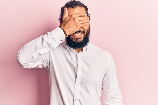 Young arab man wearing casual clothes smiling and laughing with hand on face covering eyes for surprise. blind concept.
