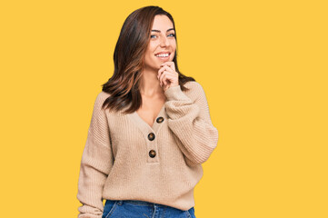 Young brunette woman wearing casual winter sweater looking confident at the camera with smile with crossed arms and hand raised on chin. thinking positive.