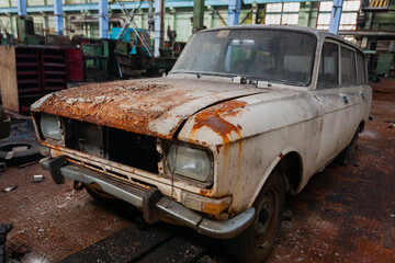 Old rusty Soviet car front view on the territory of the workshop of an abandoned old industrial plant.