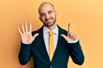 Young hispanic man wearing business suit and tie showing and pointing up with fingers number seven while smiling confident and happy.