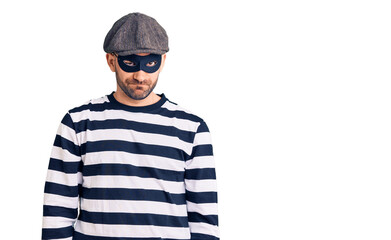 Young handsome man wearing burglar mask skeptic and nervous, frowning upset because of problem. negative person.